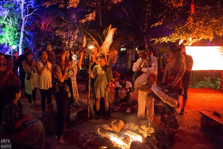 A fire ceremony at night in the jungle, drummers and the community around the flames.